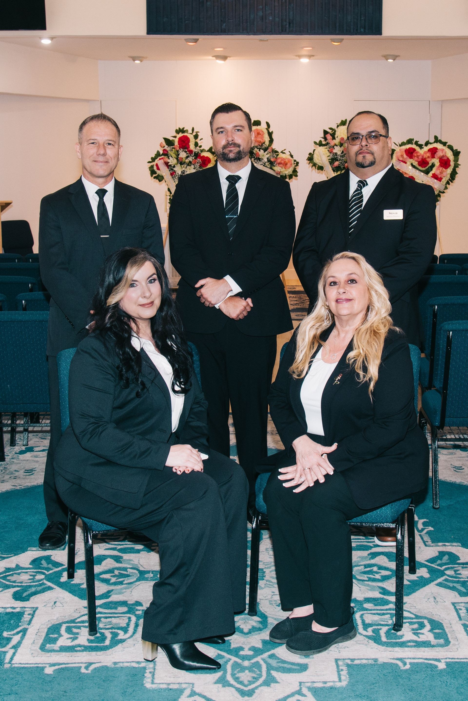 Empty chapel at Destiny Funeral Home & Crematory with rows of dark blue upholstered chairs and tiered circular chandeliers overhead