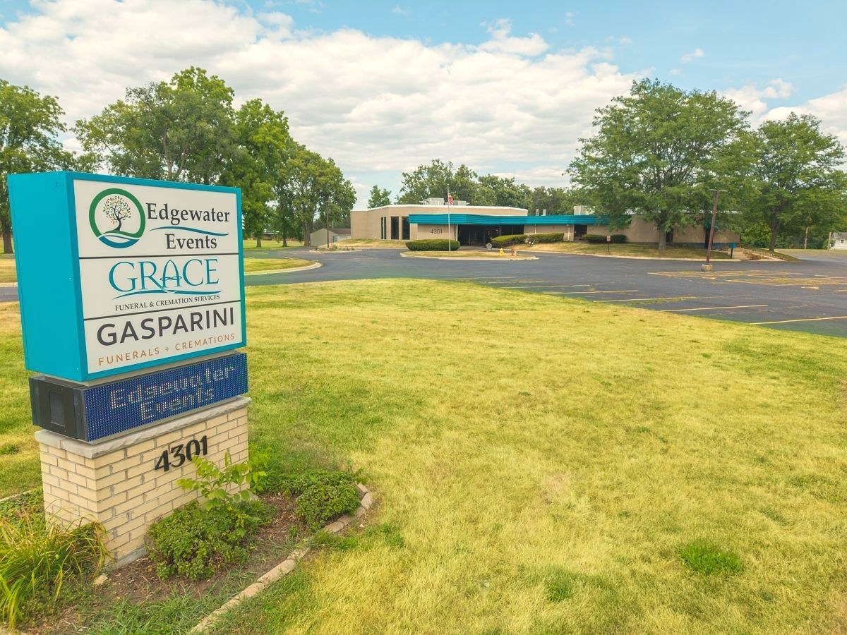 The single-story funeral home building of Grace Funeral & Cremation Services in Rockford, IL, seen from the parking lot with its teal-canopied entrance.