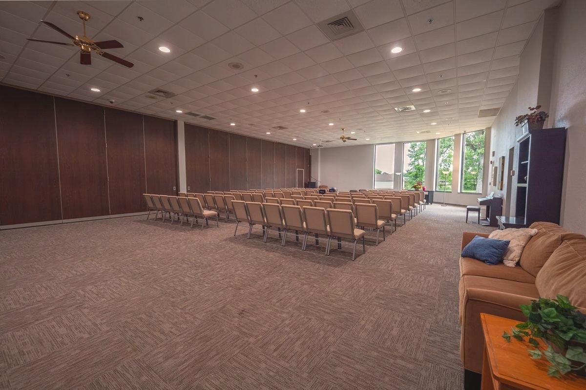 A carpeted chapel room at Grace Funeral & Cremation Services set with rows of chairs facing a podium, prepared for a memorial service.