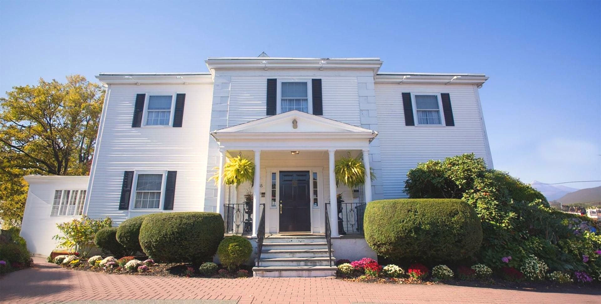 Murphy Funeral Home's white colonial-style building with black shutters and a columned front porch in Salem, Massachusetts.
