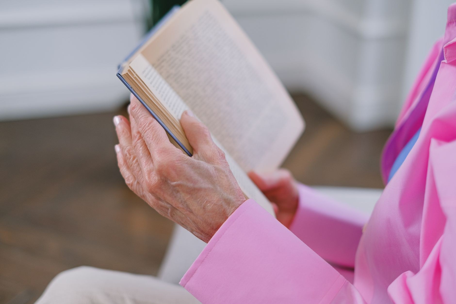 Close-up of an elderly woman's hand resting on her knee, wearing a dark, patterned cardigan.